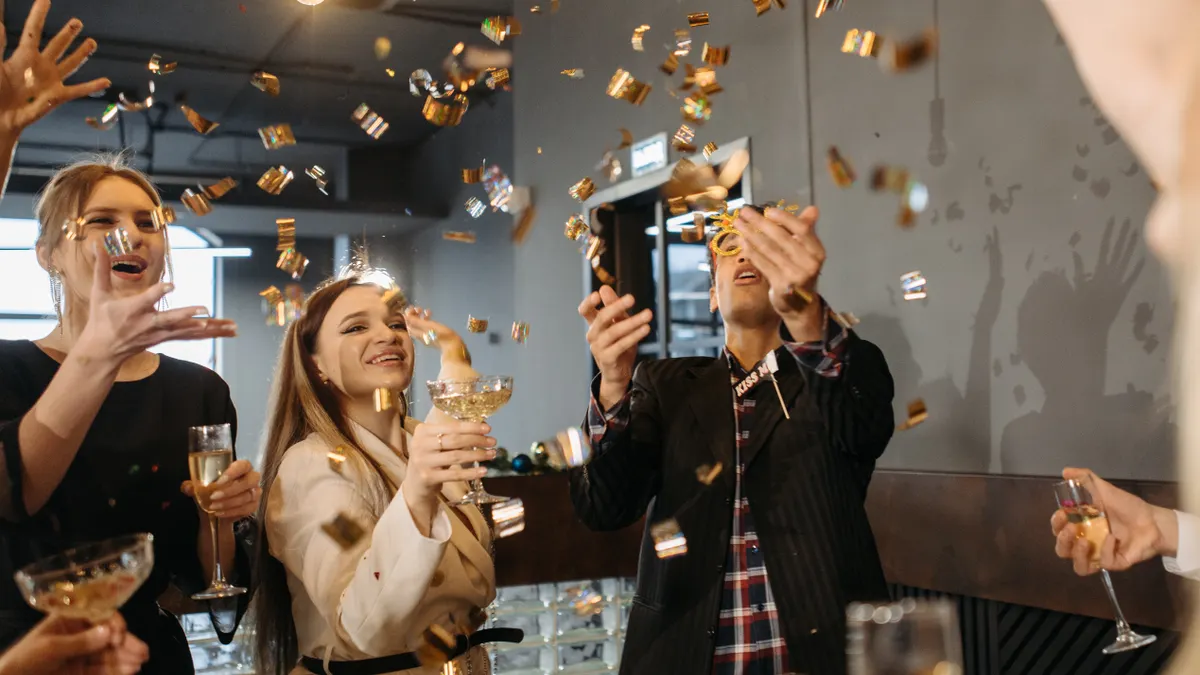 Group of colleagues celebrating indoors with champagne and confetti, capturing joy and togetherness.