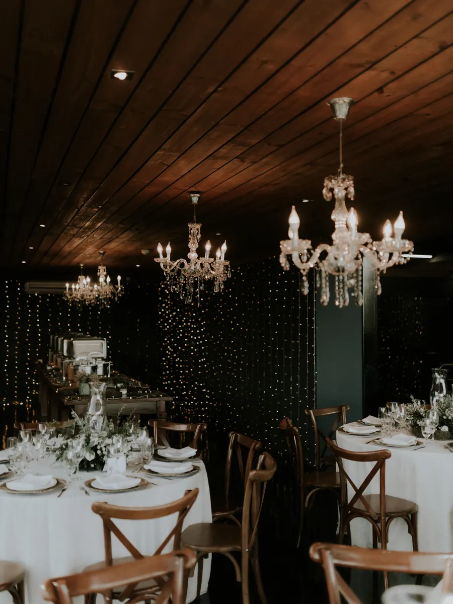 Beautifully lit banquet hall with chandeliers and round tables set for an event. Perfect for weddings.