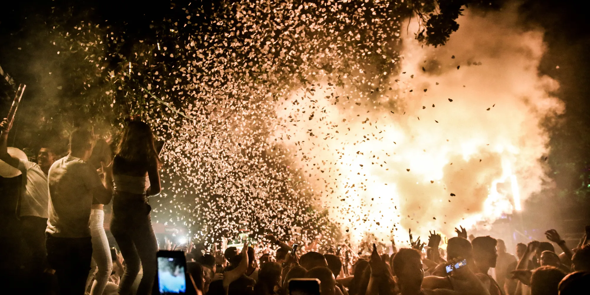 Exciting nighttime party scene with a crowd celebrating amidst a vibrant confetti burst.